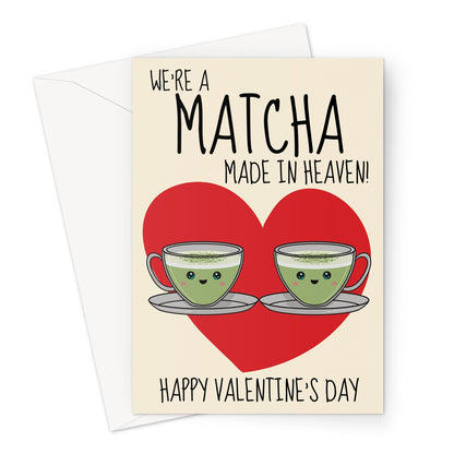 A cute Valentine's Day card featuring two smiling matcha latte cups with happy faces, placed in front of a red heart. The text reads "We’re a Matcha Made in Heaven" with "Happy Valentine’s Day" below.