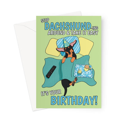 Illustrated Dachshund birthday card featuring a cute sausage dog in bed with a party hat, cupcake, and coffee, with the funny text "Stop Dachshund-ing Around & Take It Easy – It’s Your Birthday!"