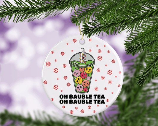 A round ceramic Christmas decoration to hang from a tree. Has a hand drawn illustration of boba bubble tea with baubles instead of tapioca bubbles.