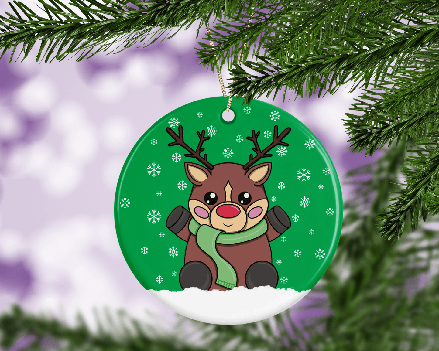 A round ceramic Christmas decoration to hang from a tree. Has a hand drawn illustration of a cute red nosed reindeer with a green snowy background.